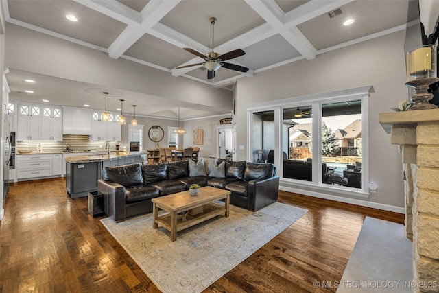 living room with ceiling fan, dark wood-type flooring, coffered ceiling, and beamed ceiling