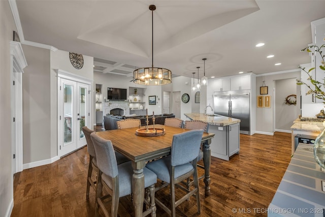 dining space featuring coffered ceiling, dark wood-type flooring, sink, beamed ceiling, and a stone fireplace