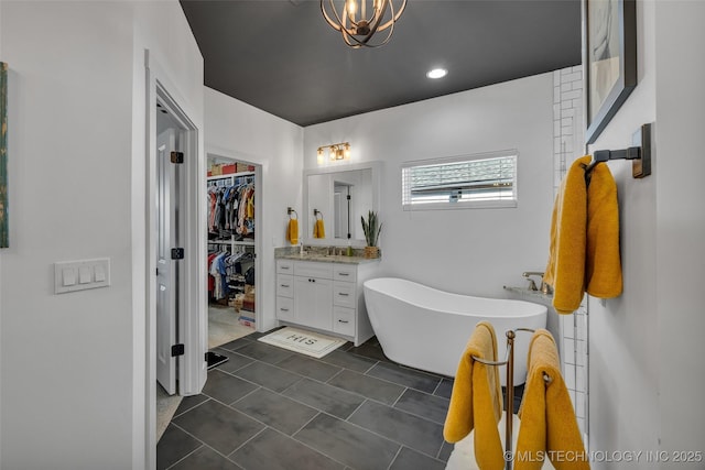 bathroom featuring vanity, an inviting chandelier, and a bath