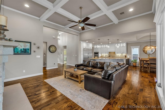 living room featuring beamed ceiling, dark wood-type flooring, coffered ceiling, and ceiling fan with notable chandelier