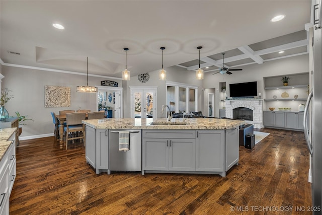 kitchen featuring light stone countertops, french doors, decorative light fixtures, and a center island with sink