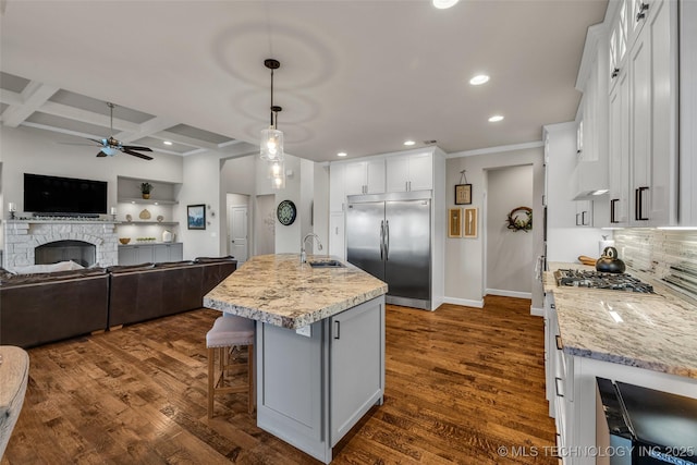 kitchen with stainless steel appliances, an island with sink, white cabinetry, coffered ceiling, and sink