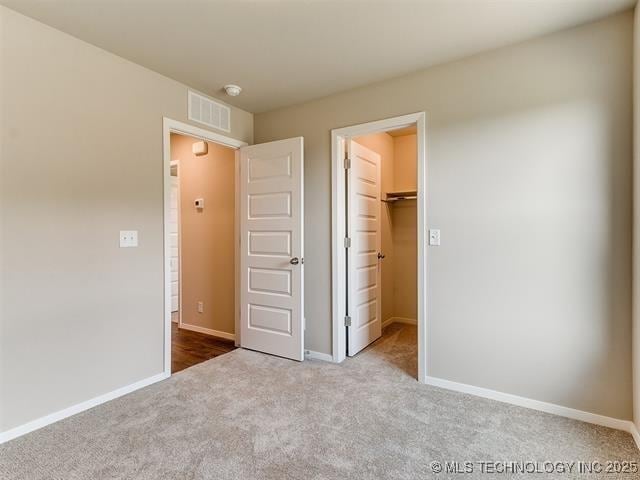 unfurnished bedroom featuring light colored carpet, a spacious closet, and a closet