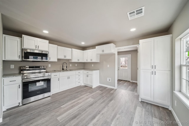 kitchen featuring appliances with stainless steel finishes, a healthy amount of sunlight, and white cabinets