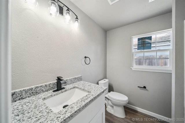 half bathroom with toilet, baseboards, wood finished floors, and vanity