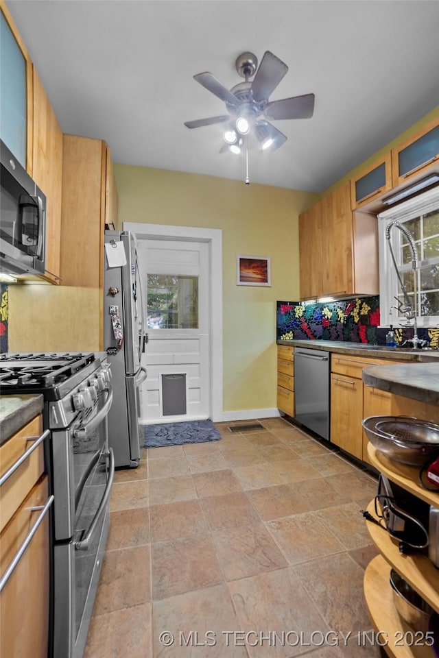 kitchen featuring ceiling fan, appliances with stainless steel finishes, backsplash, and plenty of natural light