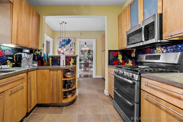 kitchen featuring decorative backsplash, sink, hanging light fixtures, appliances with stainless steel finishes, and a chandelier