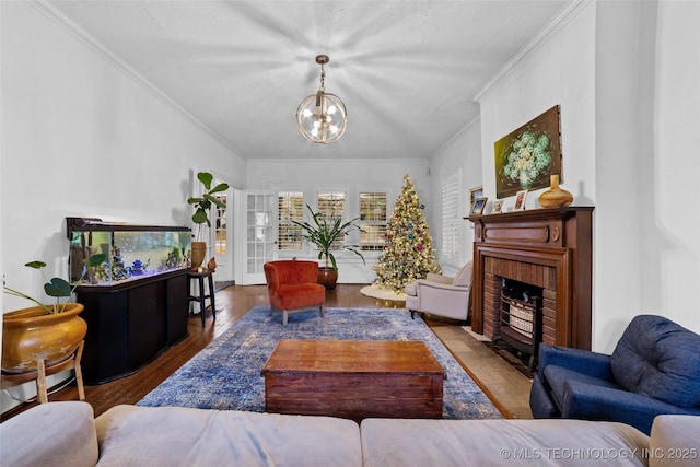 living room with a textured ceiling, a fireplace, dark hardwood / wood-style floors, ornamental molding, and a chandelier