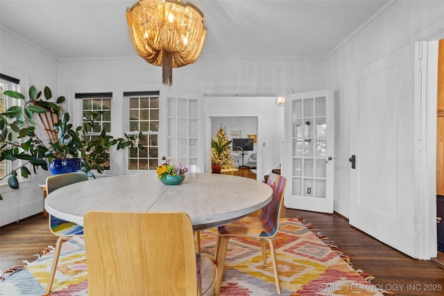 dining space with french doors, dark wood-type flooring, an inviting chandelier, and ornamental molding