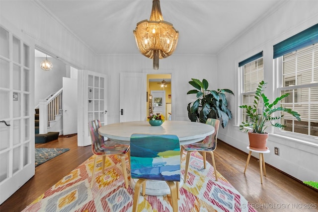 dining area with dark wood-type flooring, french doors, ornamental molding, and a notable chandelier