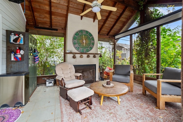 sunroom featuring ceiling fan, vaulted ceiling with beams, wood ceiling, and exterior fireplace