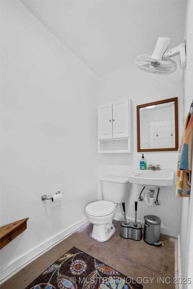 bathroom with toilet, sink, concrete floors, and lofted ceiling