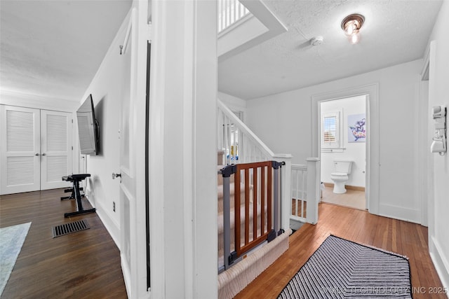 hall with hardwood / wood-style floors and a textured ceiling