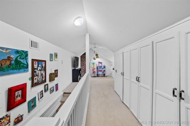 hallway with light colored carpet and lofted ceiling