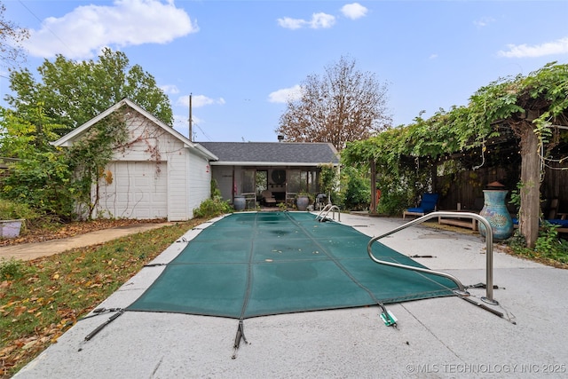 view of swimming pool with a garage, an outbuilding, and a patio