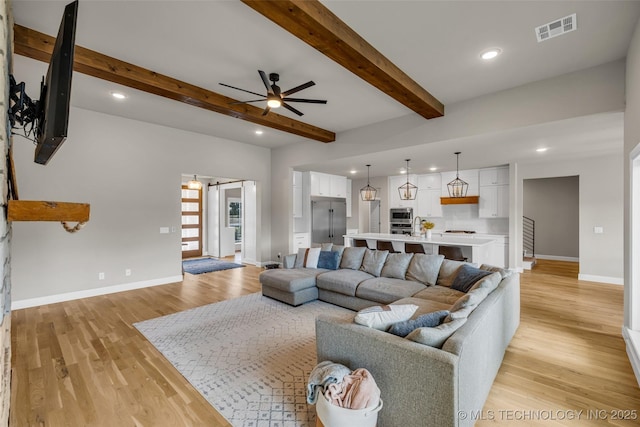 living room featuring ceiling fan, light hardwood / wood-style flooring, and beamed ceiling