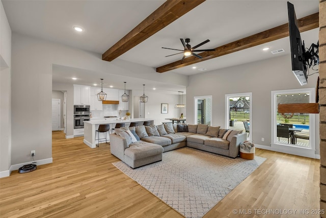 living room featuring ceiling fan, light hardwood / wood-style flooring, and beamed ceiling