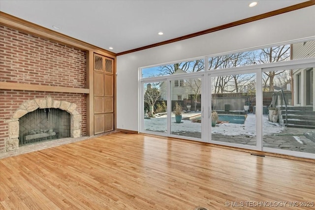 unfurnished living room featuring baseboards, ornamental molding, light wood-style floors, a fireplace, and recessed lighting