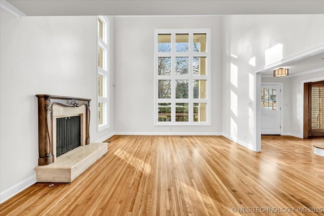 unfurnished living room featuring a fireplace, light wood-style flooring, and baseboards