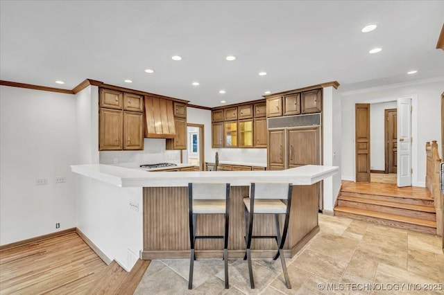 kitchen featuring light countertops, paneled refrigerator, a peninsula, and a kitchen breakfast bar