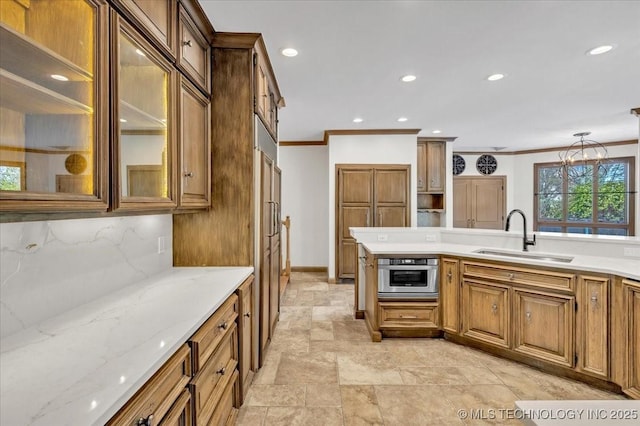 kitchen with brown cabinets, oven, a sink, crown molding, and backsplash