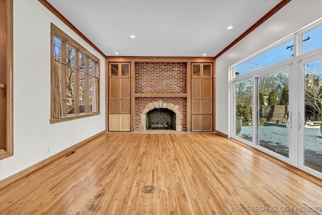 unfurnished living room featuring baseboards, visible vents, ornamental molding, wood finished floors, and a fireplace