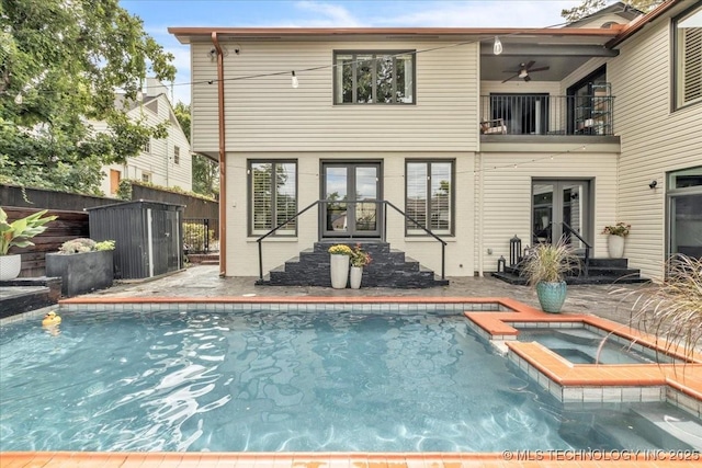 back of property featuring entry steps, a balcony, ceiling fan, fence, and a pool with connected hot tub