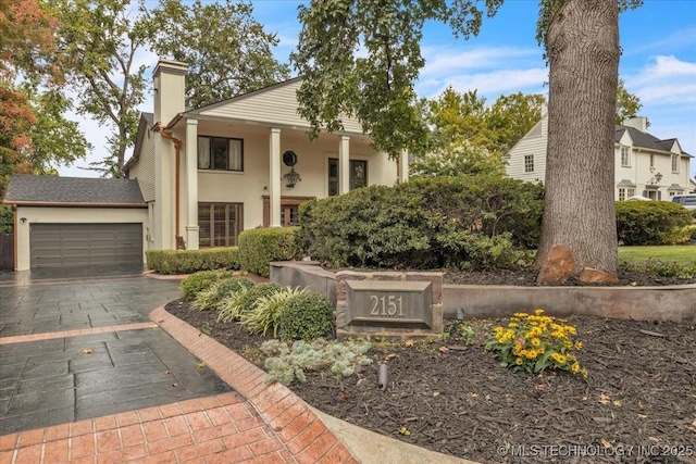 view of front of home featuring a garage, driveway, a chimney, and stucco siding