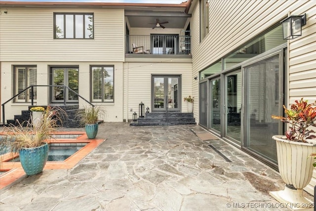 rear view of property with french doors, a ceiling fan, a patio area, a balcony, and a jacuzzi