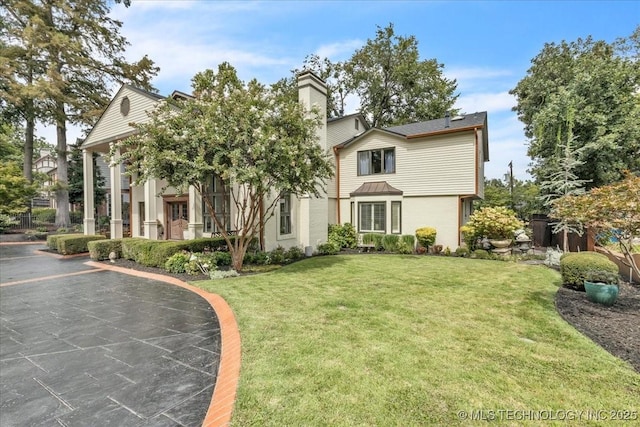 view of front of home with a chimney and a front yard