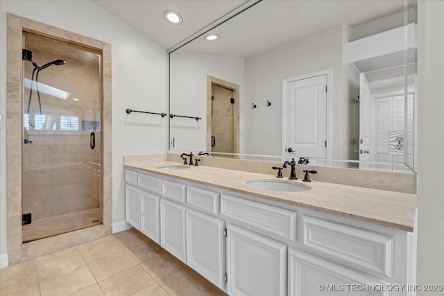 bathroom featuring double vanity, a shower stall, a sink, and tile patterned floors