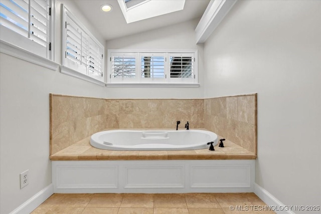 bathroom featuring lofted ceiling with skylight, tile patterned flooring, baseboards, and a bath