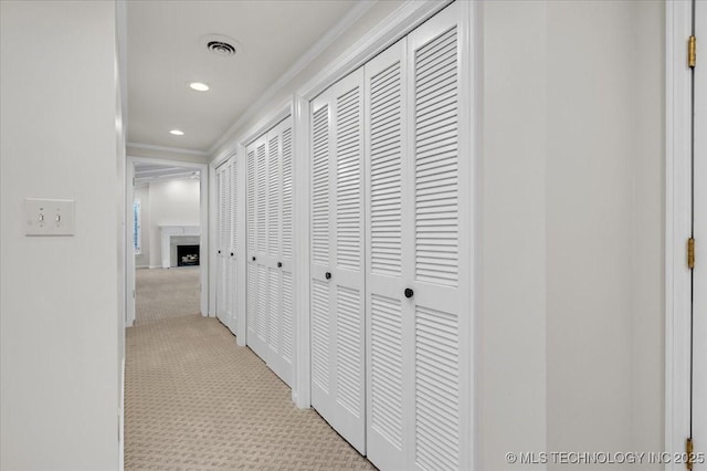 hallway with ornamental molding, recessed lighting, visible vents, and light colored carpet