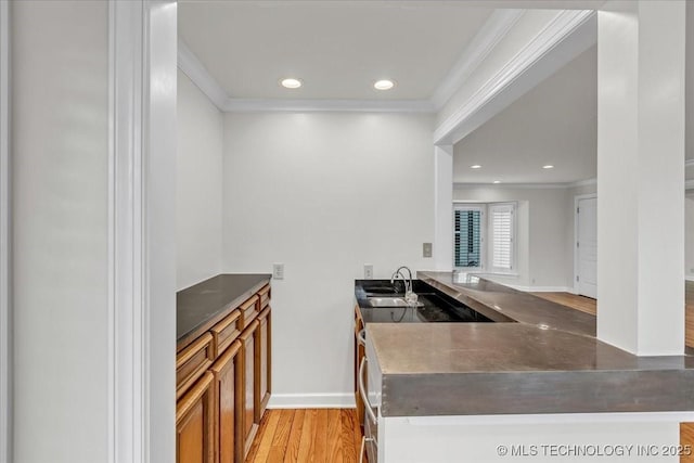 interior space with brown cabinets, recessed lighting, light wood-style flooring, ornamental molding, and a sink