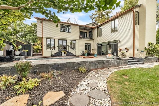 rear view of property featuring a patio, a chimney, and a balcony