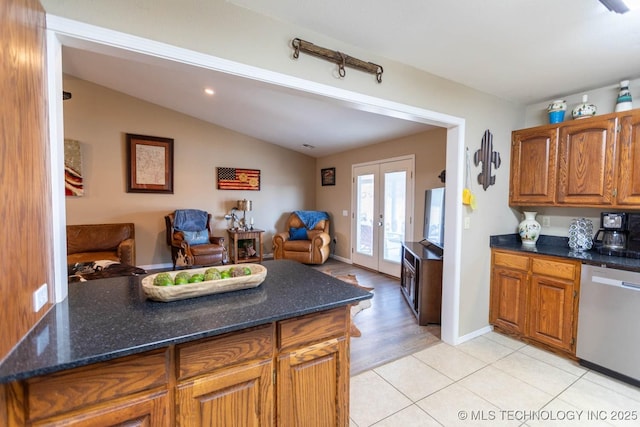 kitchen with vaulted ceiling, stainless steel dishwasher, light tile patterned flooring, french doors, and dark stone counters