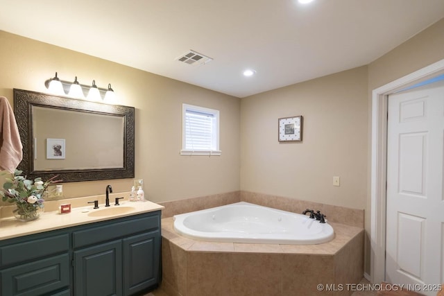 bathroom featuring tiled bath and vanity