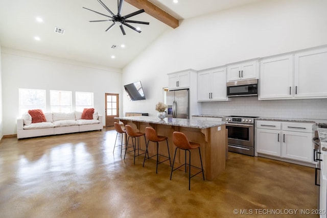 kitchen with white cabinetry, a breakfast bar, stainless steel appliances, and a kitchen island