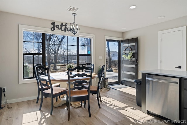 dining area with a wealth of natural light, an inviting chandelier, and light wood-type flooring