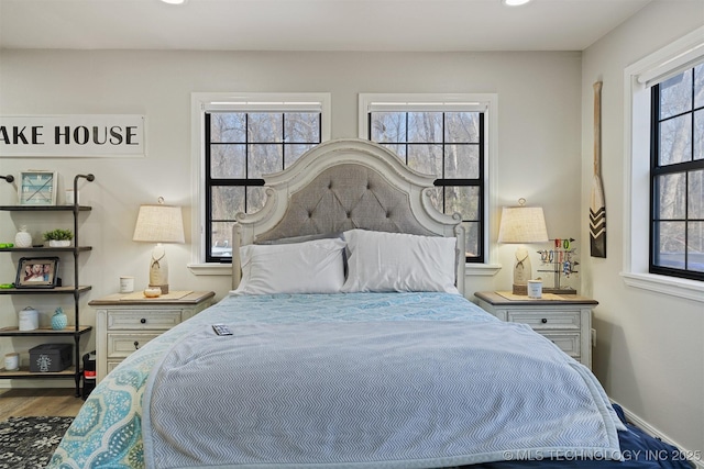 bedroom with multiple windows and hardwood / wood-style floors