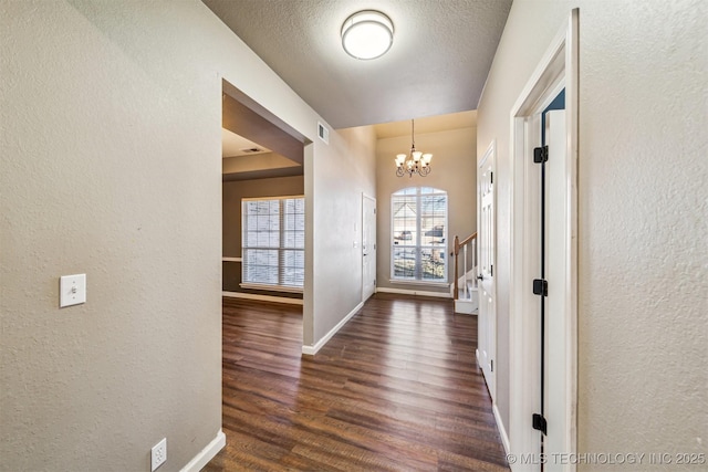 entryway featuring a textured ceiling, dark hardwood / wood-style floors, and a notable chandelier