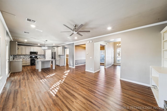 unfurnished living room featuring ornamental molding, ceiling fan with notable chandelier, and dark hardwood / wood-style floors