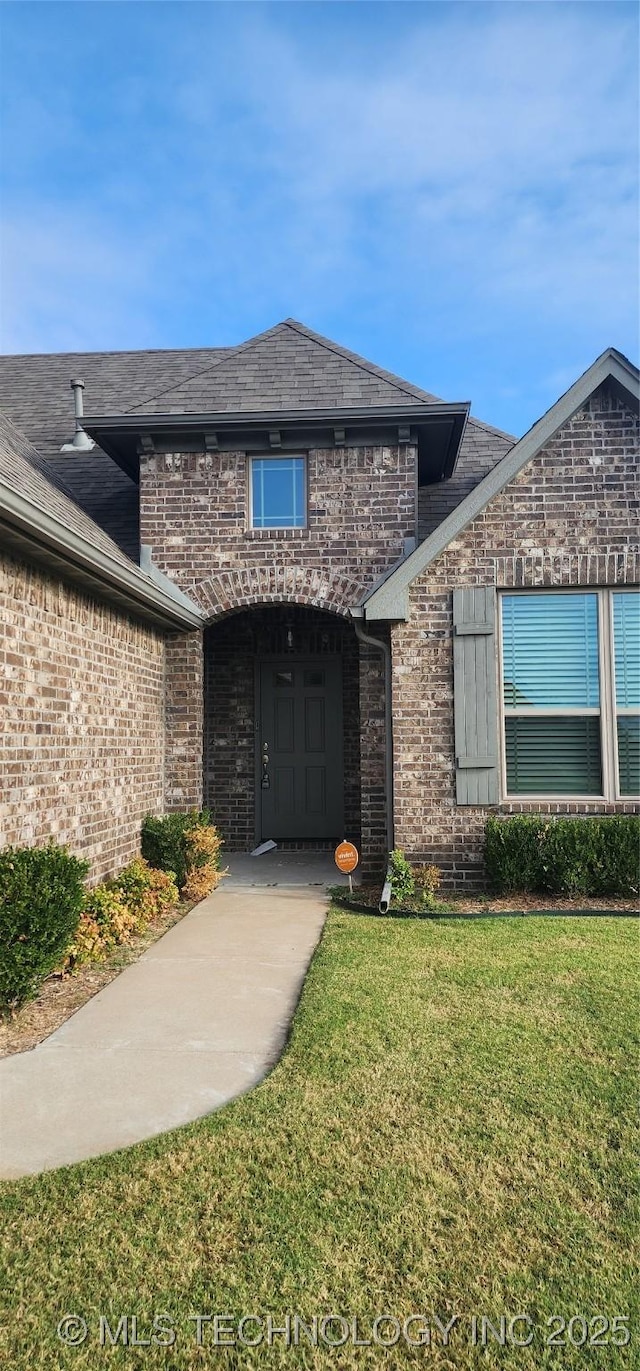 view of exterior entry featuring a lawn