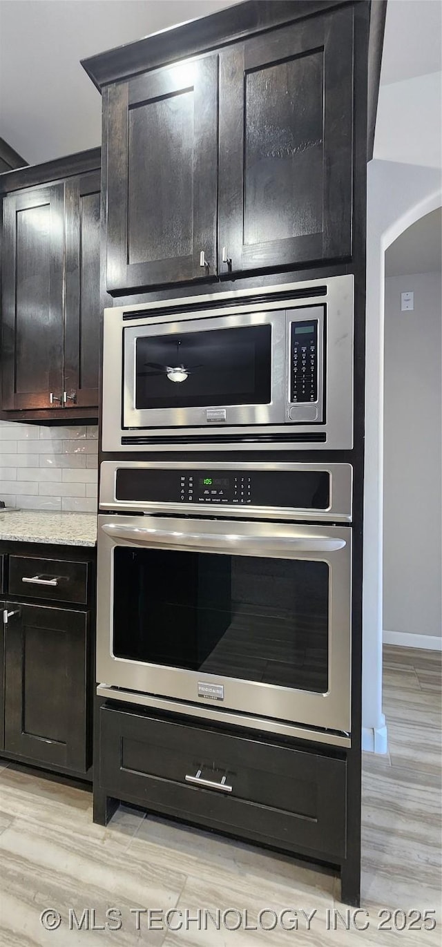 kitchen featuring decorative backsplash, light stone counters, stainless steel appliances, and light hardwood / wood-style flooring