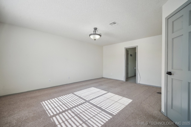 empty room with light carpet, visible vents, and a textured ceiling