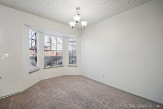 empty room with a chandelier, a textured ceiling, baseboards, and carpet floors