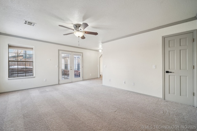 carpeted spare room featuring visible vents, ornamental molding, a ceiling fan, a textured ceiling, and french doors