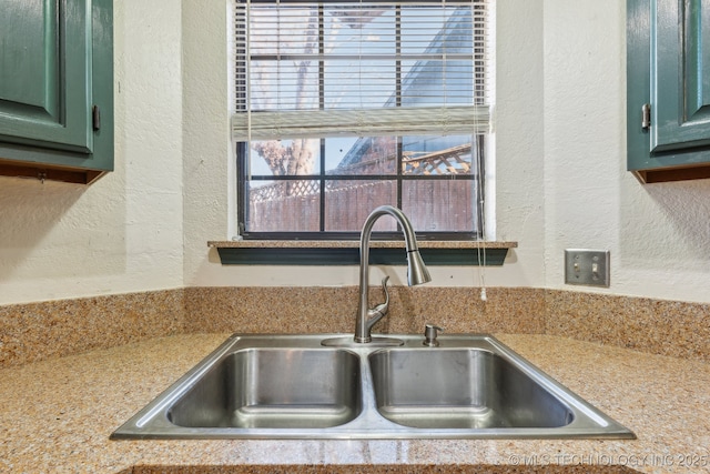 interior details featuring light countertops, a textured wall, and a sink