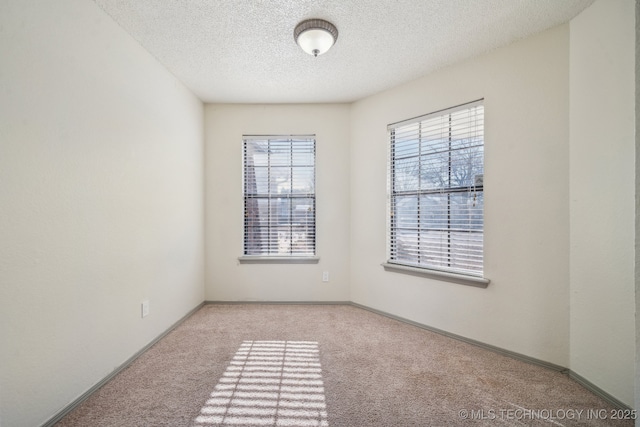 carpeted empty room with a textured ceiling and baseboards