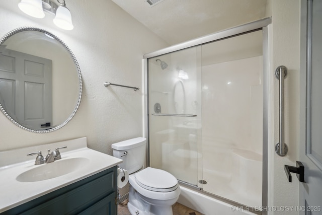 bathroom featuring vanity, toilet, a textured wall, and a stall shower